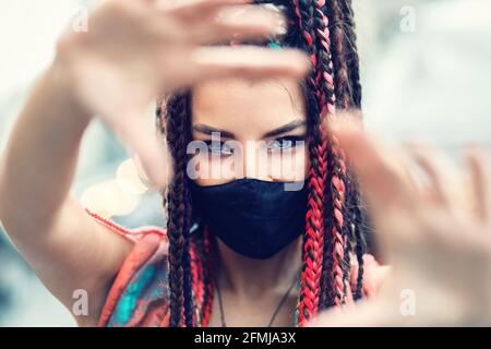 Verspielte coole Rebell funky Hipster junges Mädchen mit Gesichtsmaske Und verrückte Haare machen Selfie auf der Straße Stockfoto