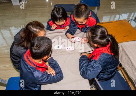 Der Lehrer beschäftigt sich mit den Schülern während eines Make-24-Kartenspiels An der BOAI Schule in Shanxi Stockfoto