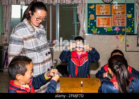Die Schüler lernen, Schleim zum ersten Mal zu machen und Führen Sie das Experiment zum Ausbruch eines Vulkans durch Stockfoto
