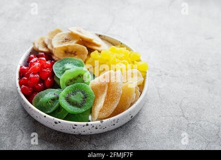 Schüssel mit verschiedenen getrockneten Früchten auf grauem Betongrund Stockfoto