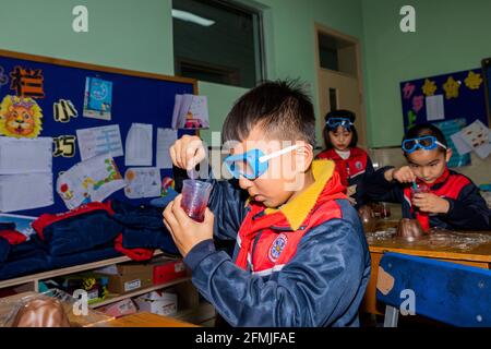 Die Schüler lernen, Schleim zum ersten Mal zu machen und Führen Sie das Experiment zum Ausbruch eines Vulkans durch Stockfoto