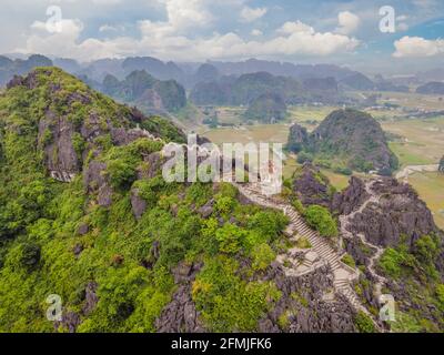 Familie von Touristen auf dem Hintergrund der erstaunlichen riesigen Drachenstatue auf Kalkstein Berggipfel in der Nähe Hang Mua Aussichtspunkt am nebligen Morgen. Beliebt Stockfoto