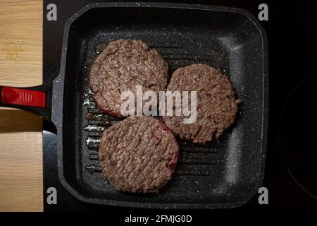 Burger Hackfleisch Fleischschnitzel auf einer Grillpfanne. Prozess der Zubereitung von selbstgemachten Burgern zu Hause. Stockfoto