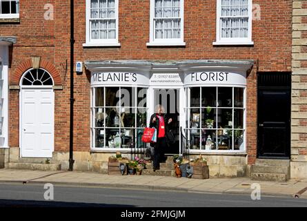 Frau, die den Floristen in der Bridge Street, Tadcaster, North Yorkshire, England, verlässt Stockfoto