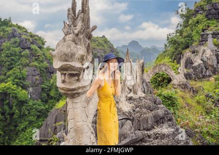 Frau Tourist auf dem Hintergrund der erstaunlichen riesigen Drachenstatue auf Kalkstein Berggipfel in der Nähe Hang Mua Aussichtspunkt am nebligen Morgen. Beliebter Tourist Stockfoto