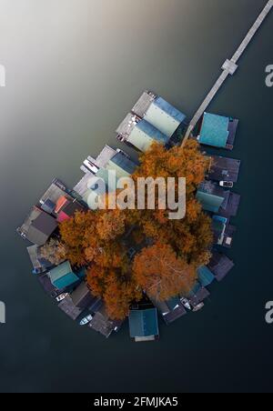 Tata, Ungarn - Luftaufnahme einer kleinen Fischerinsel am Derito-See (Derito-to) mit Herbstblättern und Laub bei Sonnenuntergang. Der See kann fo sein Stockfoto