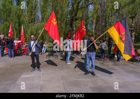 9. Mai 2021, Berlin, am sowjetischen Kriegsdenkmal im Treptower Park (Treptower Ehrenmal), einem Denkmal und gleichzeitig einem Militärfriedhof, gedenken zahlreiche Russen und Deutsch-Russen mit vielen bunten Fahnen des 76. Siegestages am Ende des Zweiten Weltkriegs. Das Denkmal wurde 1949 auf Anweisung der sowjetischen Militärverwaltung in Deutschland errichtet, um die im Zweiten Weltkrieg verstorbenen Soldaten der Roten Armee zu ehren Über 7000 der in den Schlacht um Berlin verstorbenen Soldaten sind hier begraben. Im Bild: Besucher mit Fahnen der Sowjetunion und der DDR. Verwendung worldwi Stockfoto