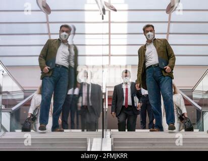 München, Deutschland. Mai 2021. Markus Söder (CSU), Ministerpräsident von Bayern, spiegelt sich im Treppenhaus der Staatskanzlei auf dem Weg zur Kabinettssitzung in Bayern, die als Videokonferenz durchgeführt wird. Hinter ihm steht Florian Herrmann (CSU), Leiter des Staatskanzleramtes und Staatsminister für Bundes- und Europaangelegenheiten und Medien. Kredit: Peter Kneffel/dpa/Alamy Live Nachrichten Stockfoto