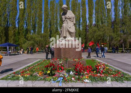 9. Mai 2021, Berlin, am sowjetischen Kriegsdenkmal im Treptower Park (Treptower Ehrenmal), einem Denkmal und gleichzeitig einem Militärfriedhof, gedenken zahlreiche Russen und Deutsch-Russen mit vielen bunten Fahnen des 76. Siegestages am Ende des Zweiten Weltkriegs. Das Denkmal wurde 1949 auf Anweisung der sowjetischen Militärverwaltung in Deutschland errichtet, um die im Zweiten Weltkrieg verstorbenen Soldaten der Roten Armee zu ehren Über 7000 der in den Schlacht um Berlin verstorbenen Soldaten sind hier begraben. Auf dem Bild die Statue 'Mutter Heimat' mit zahlreichen Blumen und Kränzen. USA Stockfoto