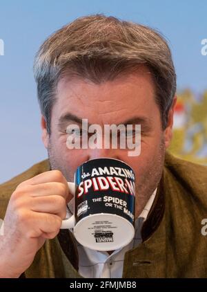 München, Deutschland. Mai 2021. Der bayerische Ministerpräsident Markus Söder (CSU) trinkt zu Beginn der Sitzung des Bayerischen Kabinetts, die als Videokonferenz durchgeführt wurde, aus einer Tasse mit dem Titel „The Amazing Spider-man“. Kredit: Peter Kneffel/dpa/Alamy Live Nachrichten Stockfoto