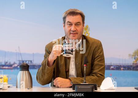 München, Deutschland. Mai 2021. Der bayerische Ministerpräsident Markus Söder (CSU) sitzt zu Beginn der Sitzung des Bayerischen Kabinetts, die als Videokonferenz durchgeführt wird, mit einem Becher in der Hand auf seinem Sitz. Kredit: Peter Kneffel/dpa/Alamy Live Nachrichten Stockfoto