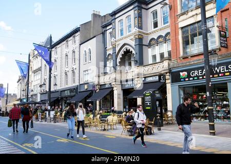 Junge Leute Frau mit Covid Gesichtsmaske Gesichtsmaske Spaziergang auf St Mary Street Geschäfte Restaurants in Cardiff City Centre Mai Frühjahr 2021 KATHY DEWITT Stockfoto