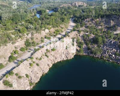 Felsige Ufer des Radon Lake an einem sonnigen Sommermorgen. Luftaufnahme eines alten überfluteten Granitsteinbruchs. Ein malerischer Teich. Stockfoto