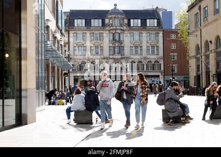 Leute, die einkaufen, spazieren gehen und an einem sonnigen Tag entspannt sitzen Springen Sie auf die Fußgängerzone vor den Geschäften im Stadtzentrum von Cardiff Mai 2021 KATHY DEWITT Stockfoto