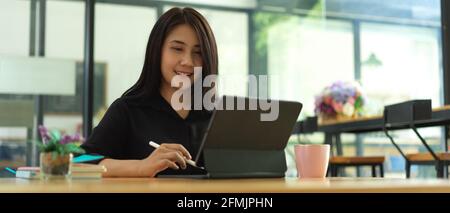 Porträt einer Büroangestellerin, die lächelt, während sie mit einem Tablet arbeitet Im Café Stockfoto