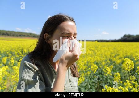 Allergische Frau, die im Frühling auf einem Feld steht und Nase bläst Saison Stockfoto