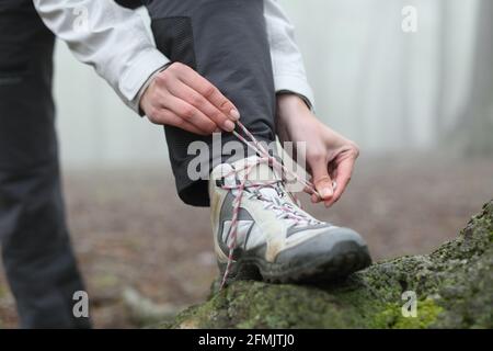 Nahaufnahme eines Wanderers, der die Schnürsenkel einbindet Der Berg Stockfoto