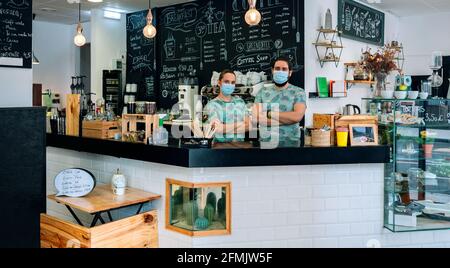 Besitzer des Cafés posieren mit Masken Stockfoto