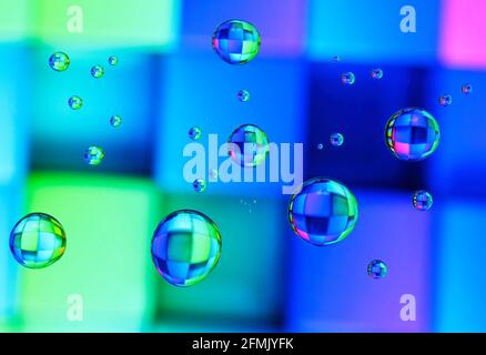 Schöne farbige Beugungseffekte von Wassertröpfchen auf Glas gegen Ein mehrfarbiger Hintergrund Stockfoto
