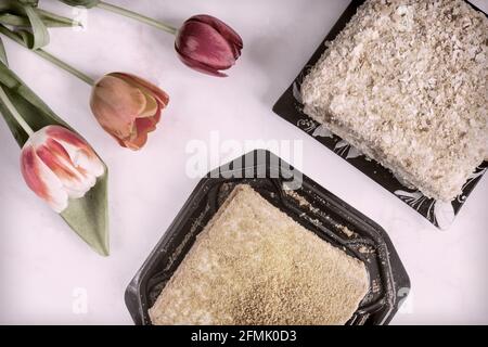 Drei rote Tulpen und ein leckerer Kuchen auf dem Festtisch. Stockfoto
