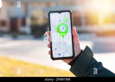 Eine Frau hält ein Handy mit den Online-Karten in der Hand App öffnen und zeigt den markierten Ort auf der Karte an.die Konzept von Online-Navigatoren und modernem techn Stockfoto
