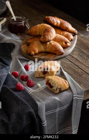 Frisch gebackene süße hausgemachte Brötchen gefüllt mit Marmelade bestreut mit Rizinuszucker, serviert auf einem rustikalen dunklen Hintergrund. Stockfoto