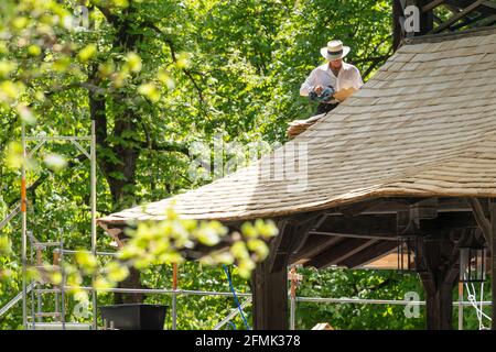 München, Deutschland. Mai 2021. Ein Mann legt neue Holzschindeln auf den 200 Quadratmeter niedrigeren Dachring des Chinesischen Turms im Englischen Garten. Der Turm gilt als eines der Wahrzeichen der Stadt und ist ein beliebter Treffpunkt im Komplex. Kredit: Peter Kneffel/dpa/Alamy Live Nachrichten Stockfoto