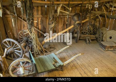 Alte Schubkarre und andere landwirtschaftliche Geräte in einer Scheune Stockfoto