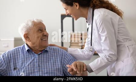 Freundliche weibliche Betreuerin unterstützt ältere Männer mit schwerer Diagnose Stockfoto