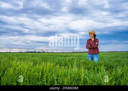 Stolze Bäuerin steht in ihrem Gerstenfeld und genießt den Sonnenuntergang. Stockfoto