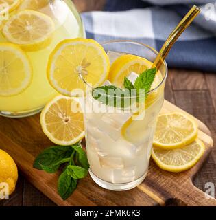 Nahaufnahme eines Glases Limonade mit Zitronenscheiben und Minze Blätter auf einem Holztisch Stockfoto