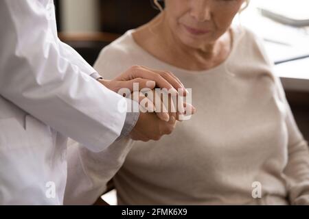 Behinderte ältere weibliche Hand in den Handflächen einer jungen Medizinerin Stockfoto