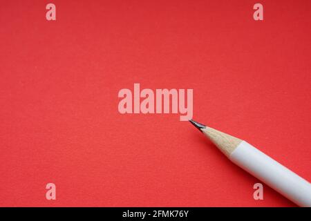 Ein weißer Bleistift auf rotem Papier, Draufsicht, Kopierbereich Stockfoto