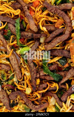 Rind- und Eiernudeln unter Rühren mit Gemüsehintergrund braten Stockfoto