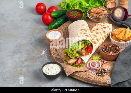 Shawarma mit truthahn, Pommes Frites und frischem Gemüse auf grauem Hintergrund. Seitenansicht, Kopierbereich. Stockfoto