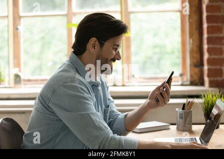 Seitenansicht lächelnder Mann mit Brille und Blick auf den Telefonbildschirm Stockfoto