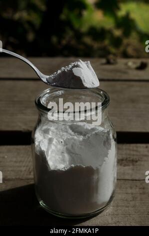 Backpulver, Mehrzweck- oder Backpulver. Von oben betrachtet auf Holzgrund. Auf einem Löffel in einem Glasgefäß Stockfoto