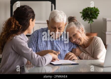 Aufgeregt gealtertes Ehepaar unterzeichnet einen finanziellen Deal mit dem Bankmanager Stockfoto