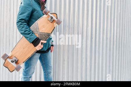 Gesichtsloses Mädchen, das ihr Skateboard hält. Platz für Text kopieren. Konzept des nachhaltigen Transports und einer gesunden Lebensweise. Stockfoto