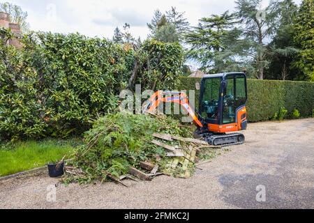 Ein Gummi-Raupenfahrzeug, ein orangefarbener Minibagger Kubota KX016-4, der für die Gartenräumung und die Beseitigung von Schutt verwendet wird, Surrey, England Stockfoto