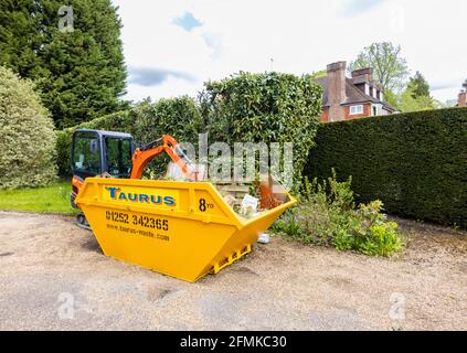 Ein Gummifahrzeug mit Raupen, ein orangefarbener Minibagger Kubota KX016-4 und ein gelber überlauf, der für die Gartenreinigung und die Beseitigung von Schutt verwendet wird, Surrey, England Stockfoto