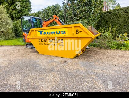 Ein Gummifahrzeug mit Raupen, ein orangefarbener Minibagger Kubota KX016-4 und ein gelber überlauf, der für die Gartenreinigung und die Beseitigung von Schutt verwendet wird, Surrey, England Stockfoto