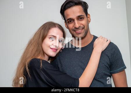 Indischer asiatischer Mann und russische weiße Frau; ein harmonisches junges Paar, das vor dem hellen Hintergrund posiert Stockfoto