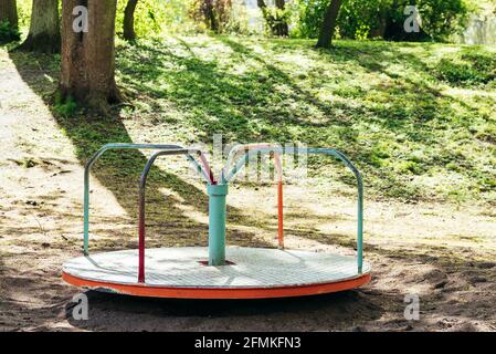 Roter und mintfarbener Spielplatz, Karussell gegen Bäume und Pflanzen Stockfoto