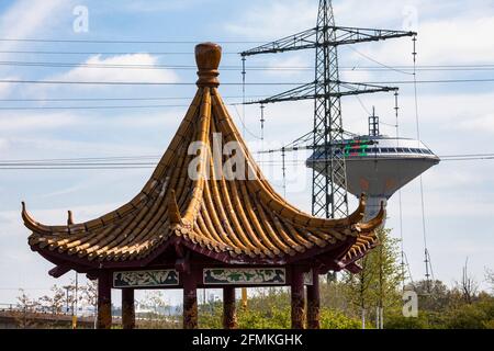 Chinesischer Drachenpavillon im Neuland-Park, im Hintergrund der Wasserturm der Energieversorgung Leverkusen und eine hohe Stockfoto