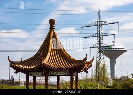 Chinesischer Drachenpavillon im Neuland-Park, im Hintergrund der Wasserturm der Energieversorgung Leverkusen und eine hohe Stockfoto