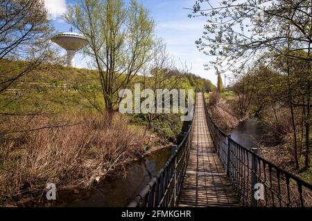 Hängebrücke über den Fluss Dhuenn im Neuland Park in Leverkusen, links der Wasserturm der Energieversorgung Leverkusen (Energieversorgung Stockfoto