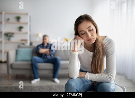 Verärgert reife Dame mit Beziehungsproblem, gehen durch eheliche Krise, ihr Mann auf Hintergrund, freien Raum. Traurige Frau, die sich deprimiert oder aus fühlt Stockfoto