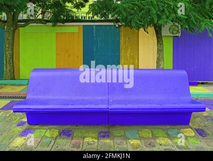 Pop Art Stil lebendige Kobalt blau leer Betonbank mit Mehrfarbige Holzwand im Hintergrund Stockfoto