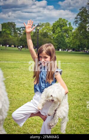 Mädchen mit Hund tut Yoga-Übungen in der Natur im Freien auf Grünes Gras auf der Fitnessmatte, Primerose Hill Park, London, Großbritannien Stockfoto